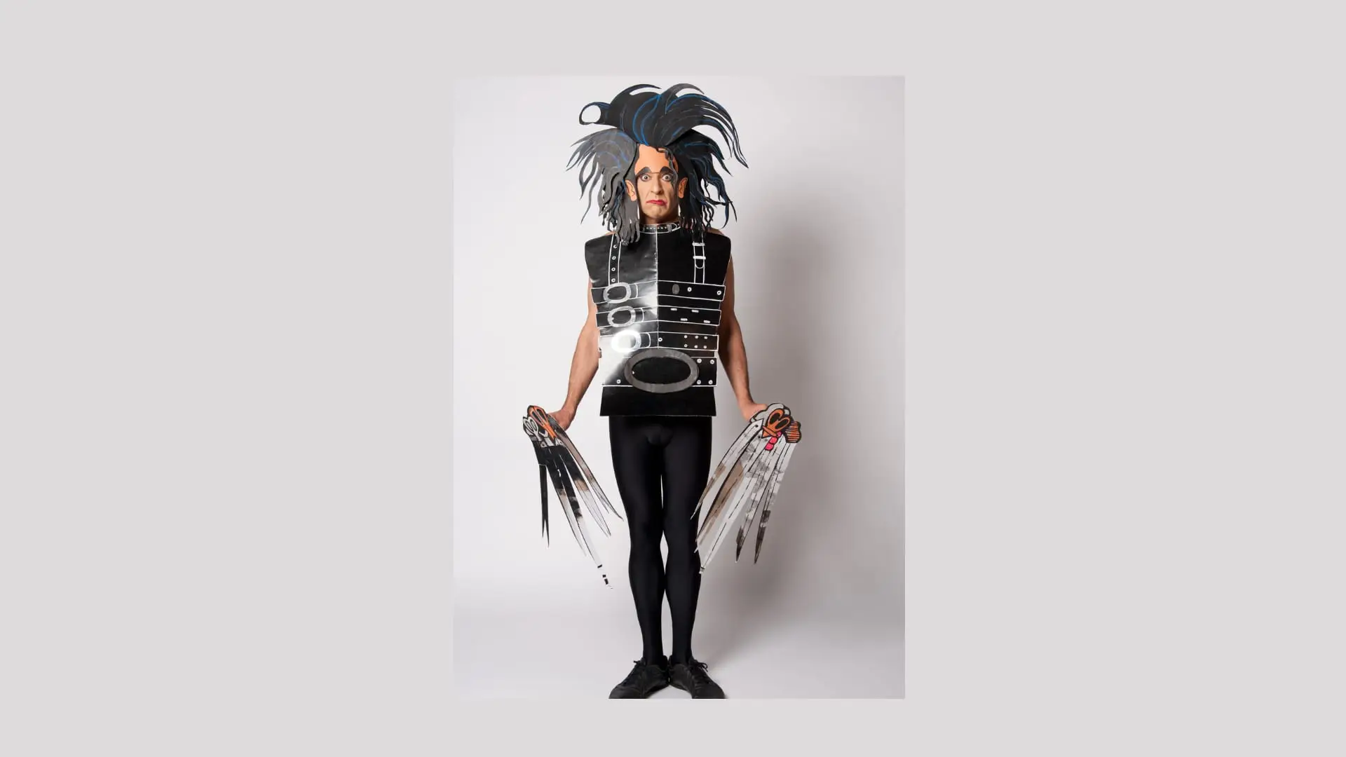 Ennio with wild black hair and paper scissor hands