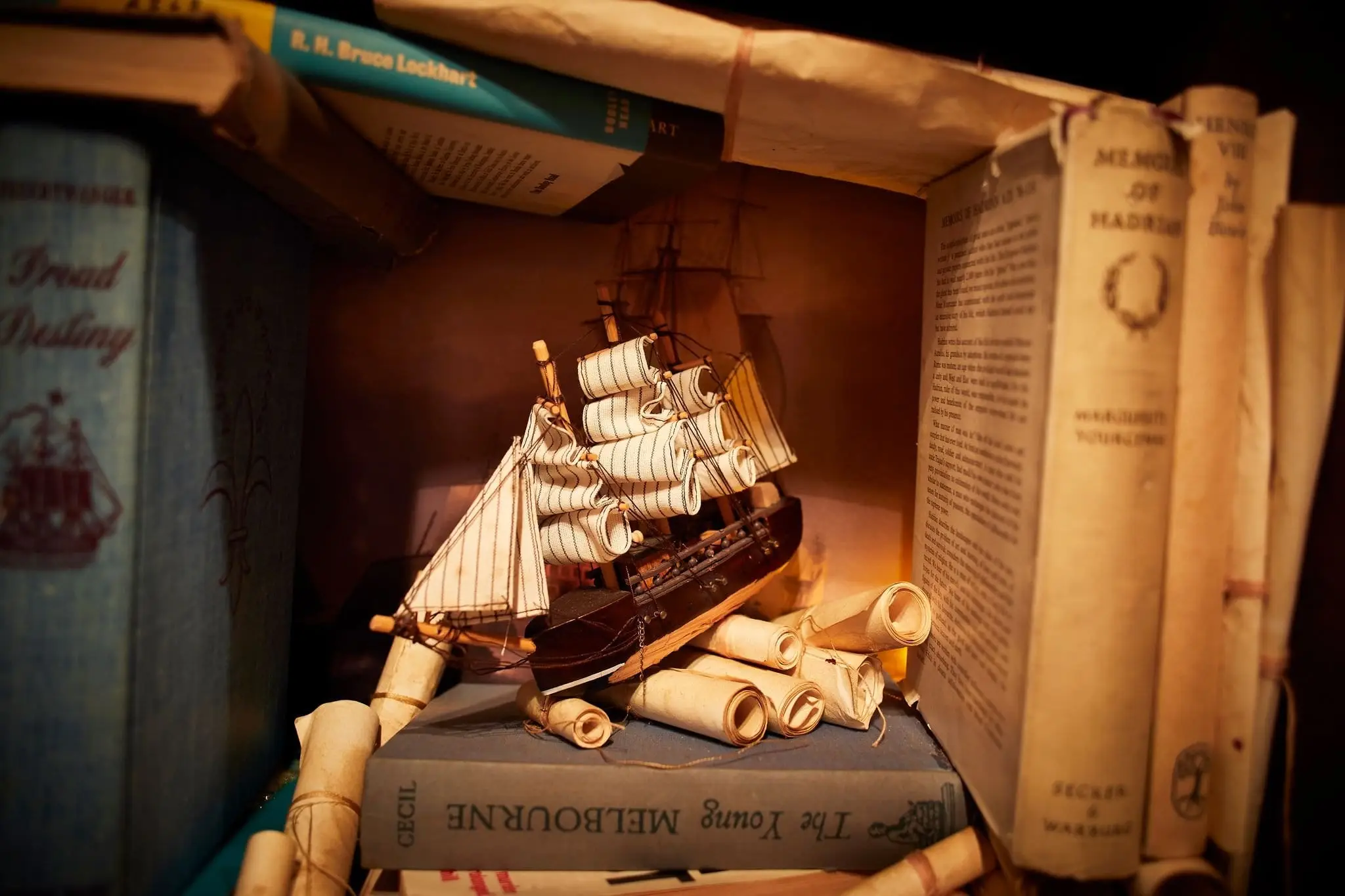 A model sailing ship perched on books and scrolls