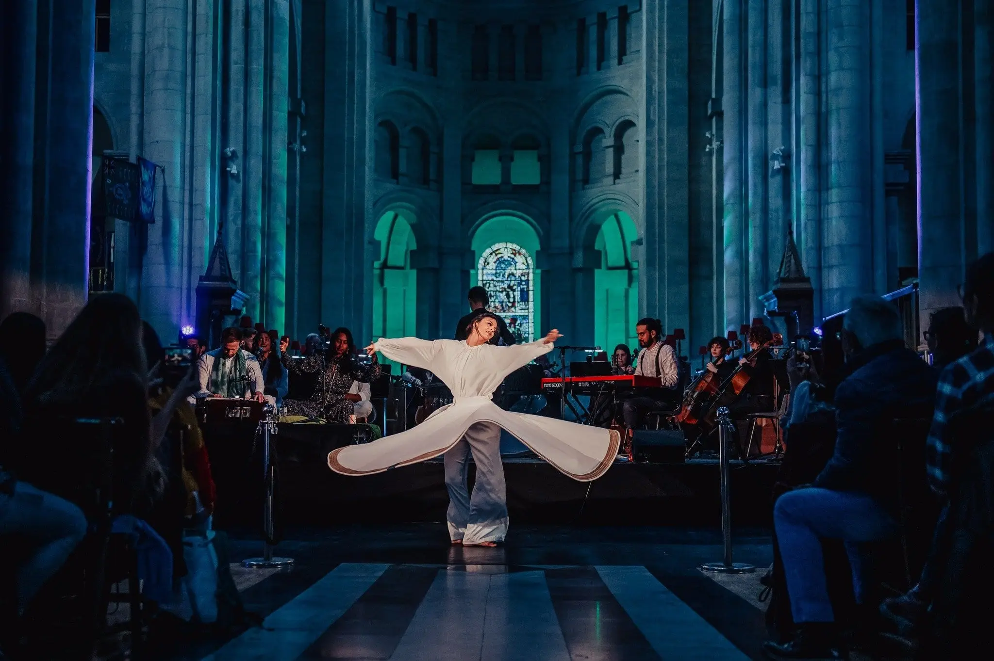 A whirling dancer in a candle-lit church with musicians either side
