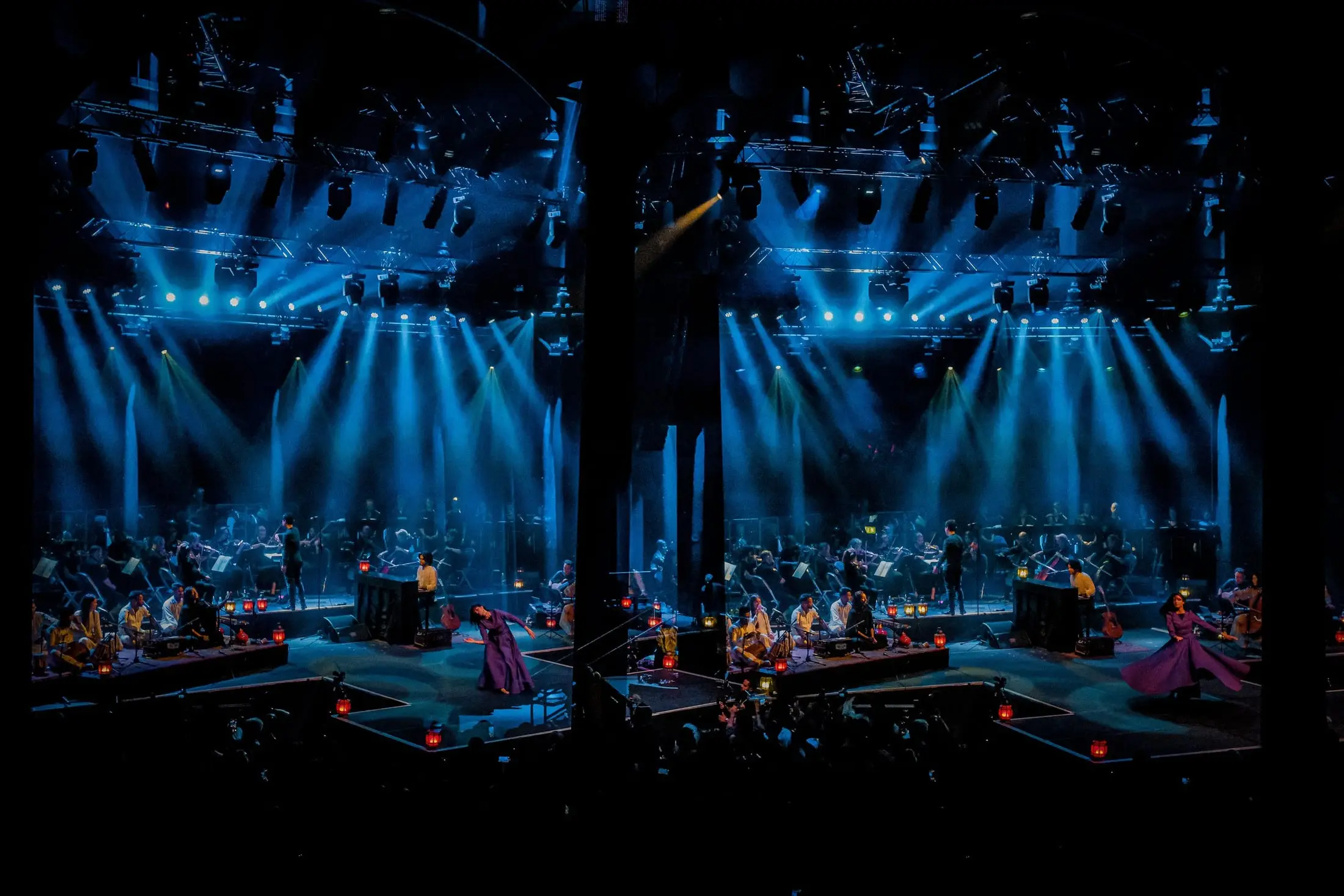 The stage lit by beams of light, the orchestra and singers in silhouette