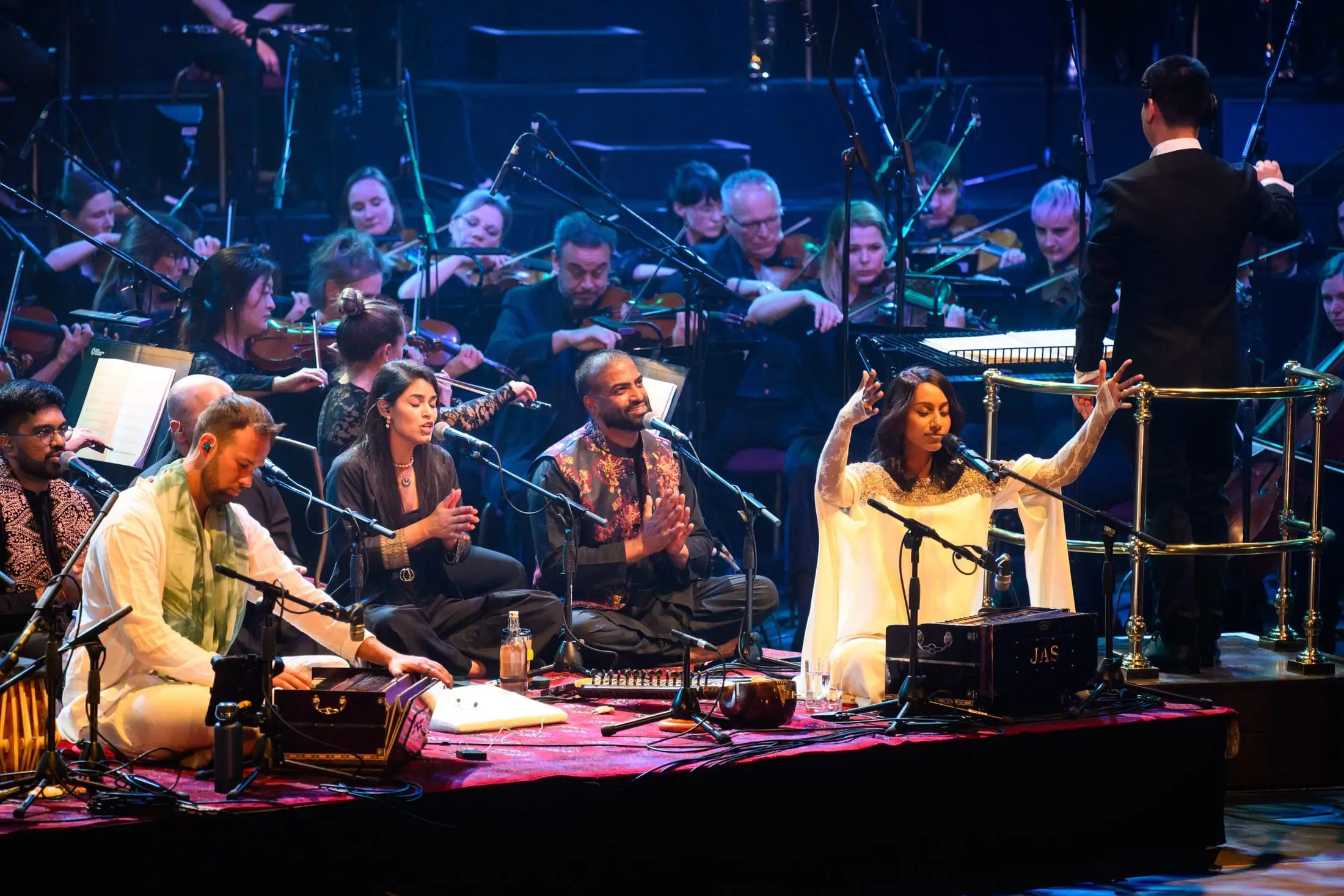 Singers and musicians on stage with the orchestra behind