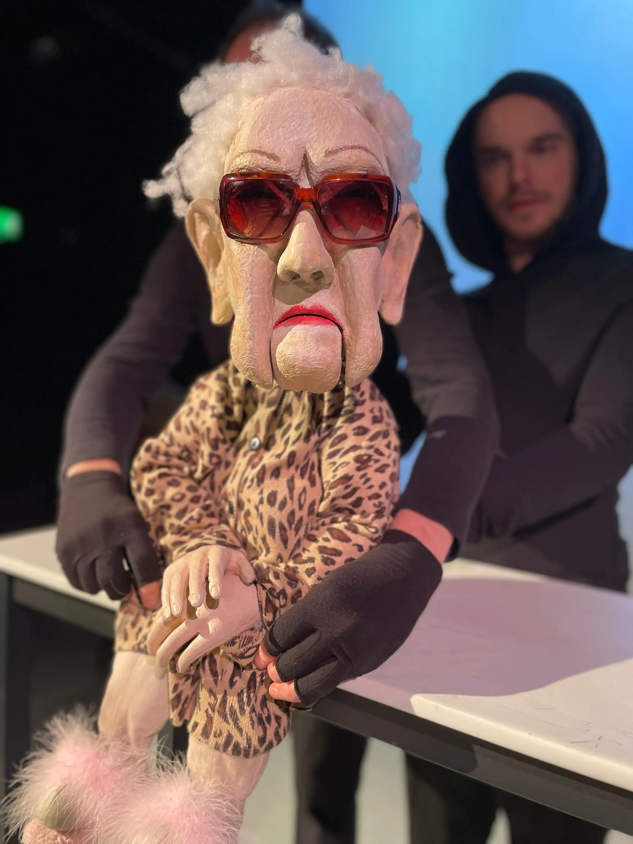A grey-haired puppet in sunglasses and a leopard-print coat
