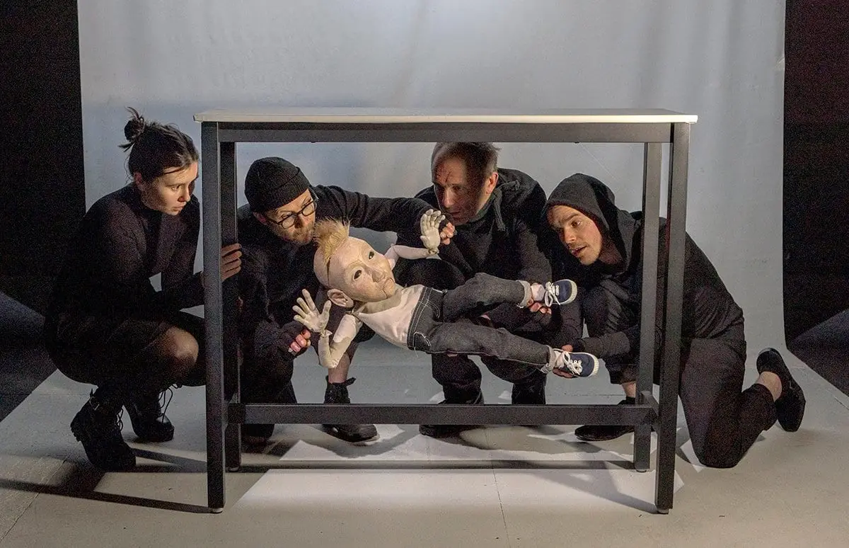 Puppeteers working a puppet through a table frame